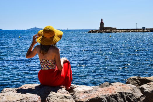 A woman in a summer hat admires the sea view at Provence-Alpes-Côte d'Azur, France.
